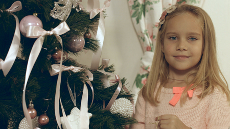 Beautiful blue-eyed girl hangs homemade Christmas toy on Christmas treeの写真素材