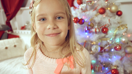 Happy little girl rejoices with gift near the Christmas treeの写真素材