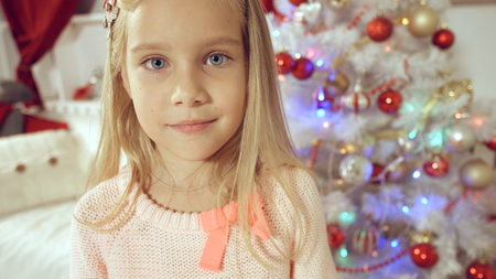 Happy little girl rejoices with gift near the Christmas treeの写真素材