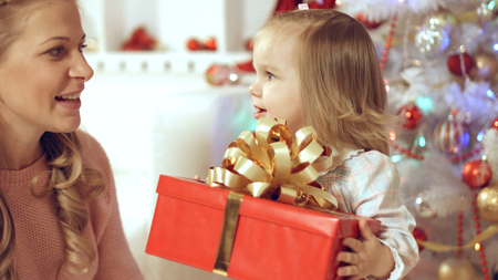 Happy family with two young daughters near the Christmas decorated tree with giftsの写真素材