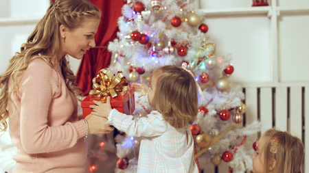 Family consists of females sitting around the Christmas tree with giftsの写真素材