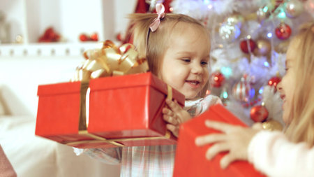 Family consists of females sitting around the Christmas tree with giftsの写真素材