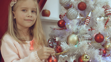 Little girl decorates the Christmas tree with bright toysの写真素材