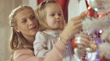 Mother with adorable baby decorate a Christmas tree at homeの写真素材