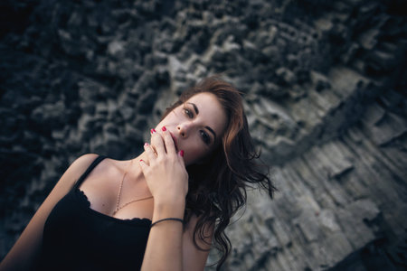 Sexy model in dress posing against the backdrop of the rock