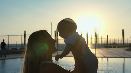 Silhouette of the mother with her little son in her arms at sunsetの写真素材
