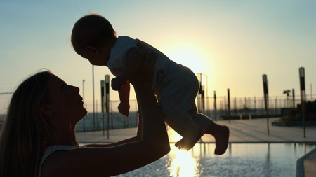 Silhouette of the mother with her little son in her arms at sunsetの写真素材