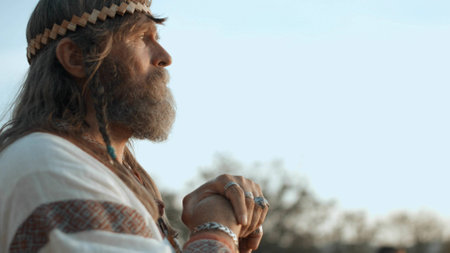 Old pagan in medieval clothes standing and looking into the distanceの写真素材