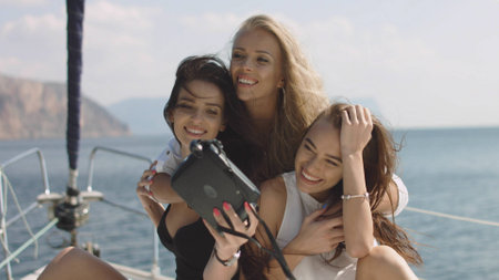 Girls taking selfies on yacht. Young models on vacationの写真素材
