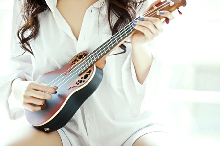 The Shot of a girl in the white shirt playing ukulele. の写真素材