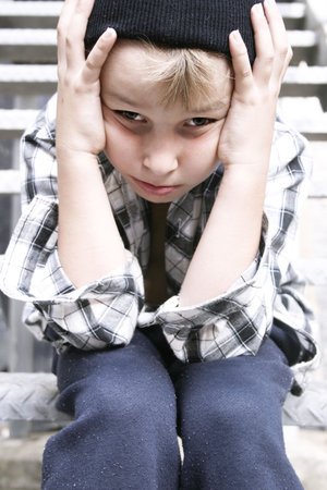 Depressed street kid sits on a fire escape stairs of grungy backlaneの写真素材