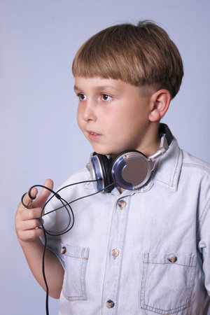 a boy with headphones around neck and twirling between his fingers.の写真素材
