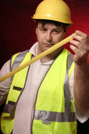 Builder with his trusty tape measure on a black/red backgroundの写真素材