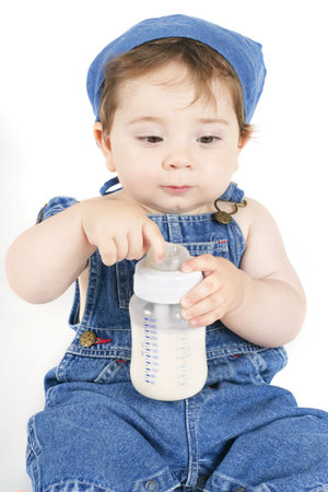 Sitting baby playing with a bottle of milkの写真素材