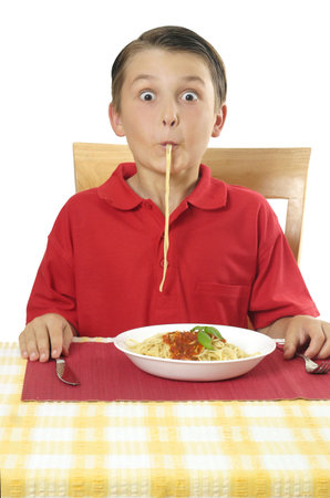 A child sucking spaghetti pasta through lips and with silly expression.の写真素材