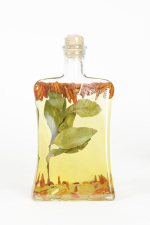 A glass bottle filled with grapeseed oil, garlic, chilli peppers and bay leaves.の写真素材