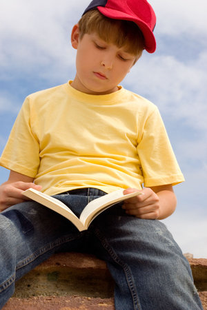Child passing time, reading a book in the sunshine