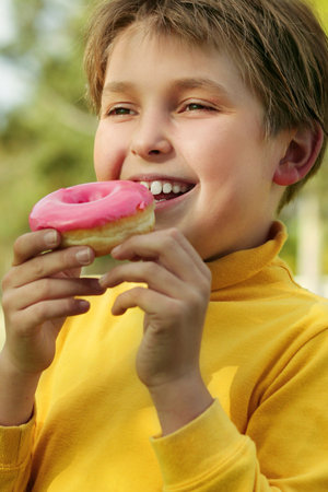 A child eating a pink iced doughnutの写真素材