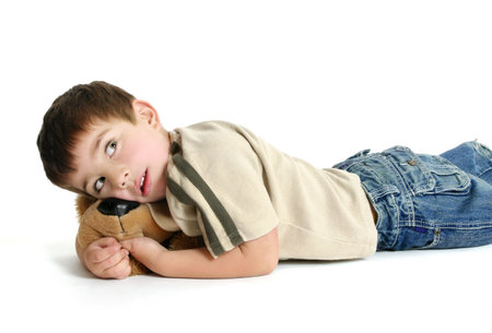Toddler boy lying on the floor with a toy and thinking.の写真素材