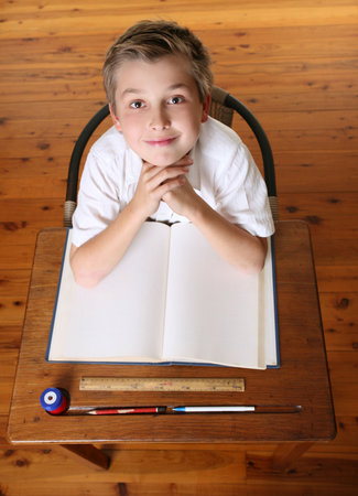 Confident school boy sitting in class with open book.の写真素材