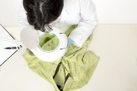 A forensic investigator observes and obtains samples from a shirt for further analysis.の写真素材