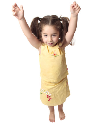 Little toddler girl with both arms raised above her head.  She is smiling and has hair in ponytails, の写真素材