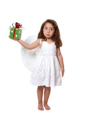 Little girl in feathered angel wings and white dress holds a present or giftの写真素材