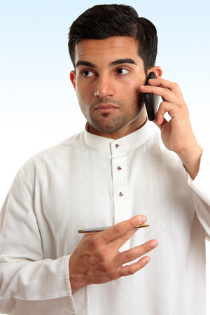 Ethnic mixed race businessman wearing traditional robe is using a mobile phone and looking sideways. Ethnic mixed race businessman wearing traditional robe is using a mobile phone and looking sideways.