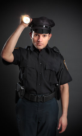 A policeman, night patrolman or security guard shining a flashlight torch to investigate or search.の写真素材