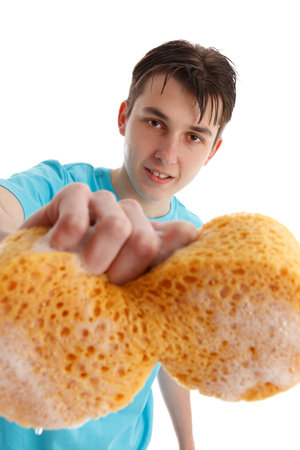 Closeup of an teen boy with outstretched hand holding a soapy sudsy sponge to clean.の写真素材