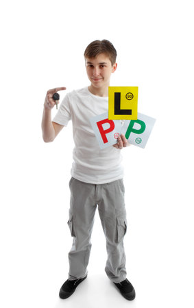 Full length teenager.  He is holding a car key and various licence plate signs for learner drivers.  White background.の写真素材