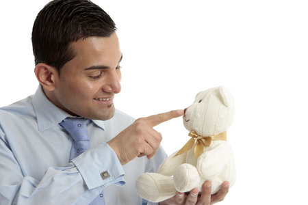 Smiling businessman or salesman touching the nose of a cream wool knitted teddy bear.の写真素材