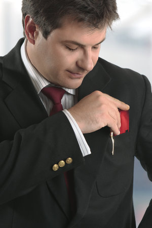 A smartly dressed man putting a business card, credit card or other type of  card into his top jacket pocket.の写真素材