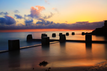 Spectacular sunrise at the Coogee Baths, south side, Coogee, Australia   The sun lit up the summer sky   Long exposure の写真素材