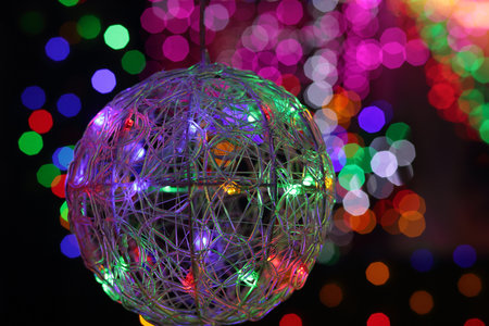 BEAUMONT HILLS, AUSTRALIA - DECEMBER 24, 2015;  Christmas wire mesh bauble ball in foreground with defocused colorued led lights in background - bokehのeditorial素材