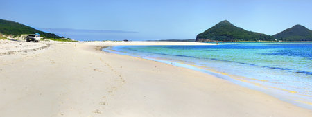 Beautiful blue waters and almost white sands at Jimmys Beach Hawks Nest panorama with Mt Tomaree in view.   A popular place for fishermen and lovely place to swim.の写真素材
