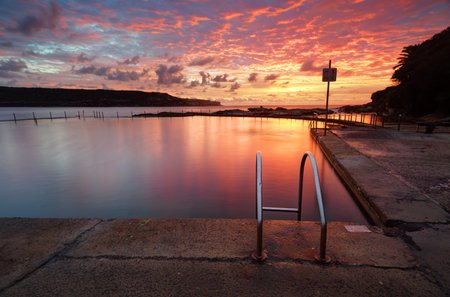 Beautiful red sunrise over Malabar Ocean Rockpool in Long Bay near Sydney Australiaの写真素材