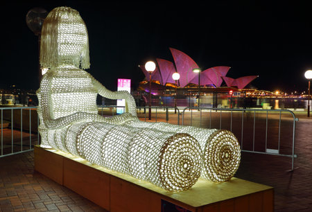 SYDNEY AUSTRALIA  MAY 27 2015   Spectators wander around the various lighting displays along the harbour foreshore.  Dolly in foreground is a large 3metre tall lightup doll made entirely from crochet and in the background the Sydney Opera House sails are のeditorial素材