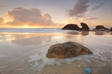 Summers sunrise at Lighthouse Beach Port Macquarie on mid north coast Australia.   A high tide brought in blue jelly blubber jellyfish.  There is motion in the tidal flowsの写真素材