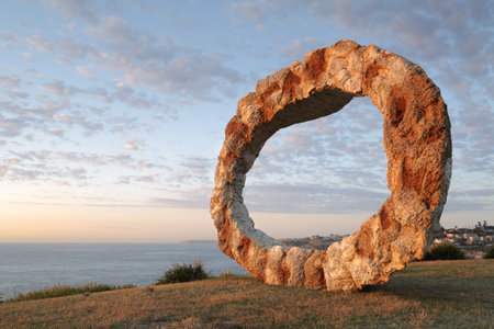 BONDI, AUSTRALIA - OCTOBER 25, 2015;  Annual Sculpture by the Sea free public event.  Exhibit titled Open by Peter Lundberg made of cast concrete with early morning sunlight touching its eastern faceのeditorial素材