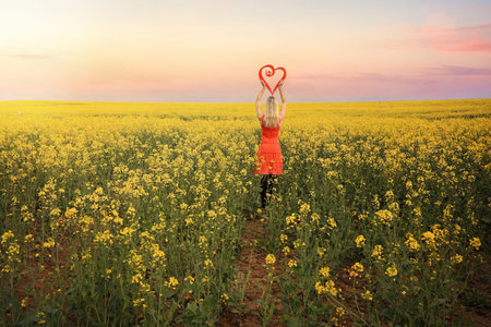 Loving springtime in Young, Hilltops Region, Country NSW.  Standing with a red heart in flowering canola as far as the eye can seeの写真素材