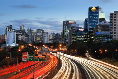 Traffic lights streak along the expressway into and out of the city at dusk.  Sydney icons, like...