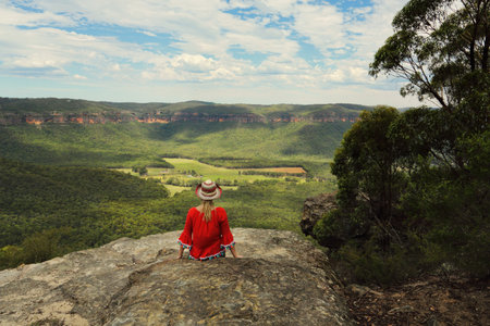 Woman relaxing with a beautiful vista of blue mountains cliffs and valley viewsの写真素材