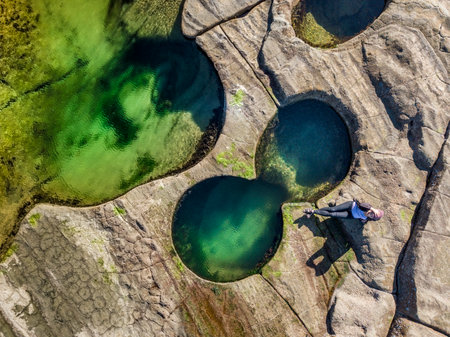Relaxing poolside, coastal rock pools glistening in vibrant jewl-like colours on the coastal rock shelf/  Deep pools of water made by nature and enjoyed in the Autumn sunshineの写真素材