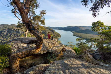 Female sitting on a large rock relaxing in afternoon dappled light the Australian bushland with views over the riverの写真素材
