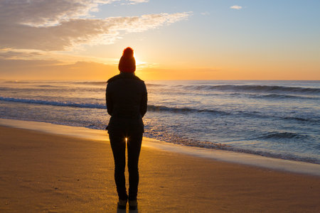Watching the sunrise on a winters morning down at the beach, the golden sands glistening in the early morning sunshineの写真素材