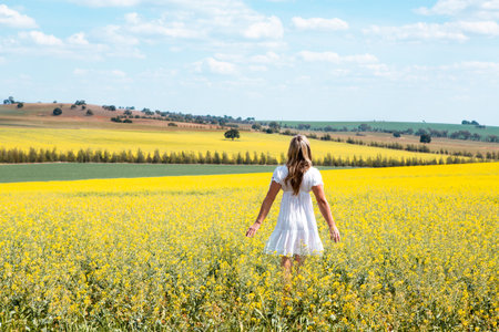 Woman wanders in fields of flowers.  She is wearing a simple white cotton dressの写真素材