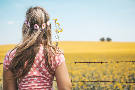 Woman standing by fields of flowering canola in Spring.の写真素材