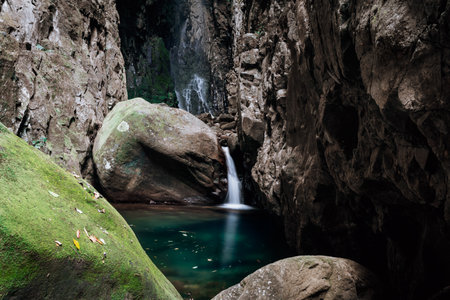 Little waterfall into pretty secret rock pool with towering rocks all aroundの写真素材