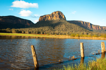 Flooded farms after heavy rains up to the fence line.  Rising irregular shaped cliffs in the backgroundの写真素材